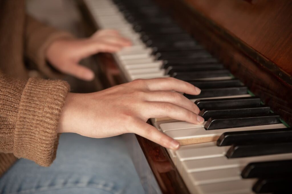 Hands playing the piano during music therapy in hospice care